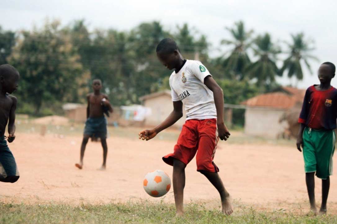 Boys playing soccer in village